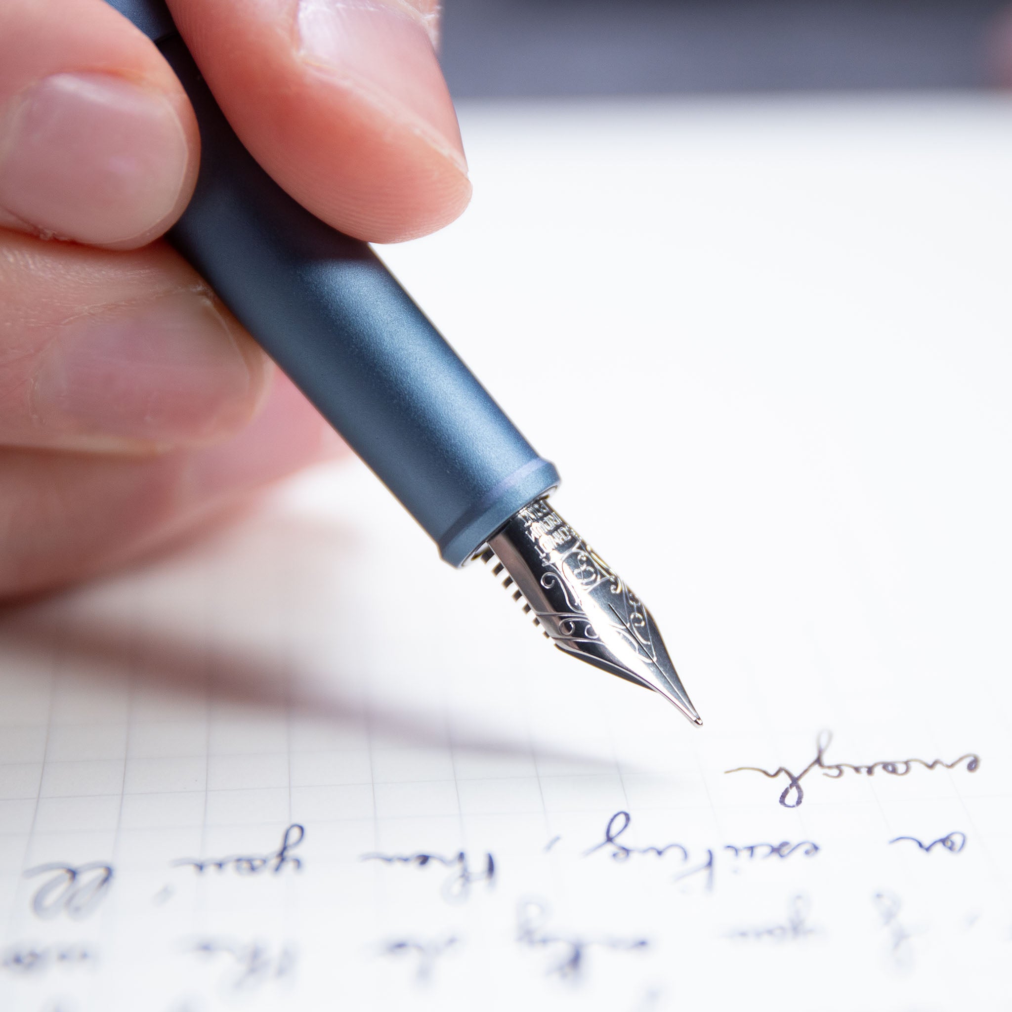 close up of a hand writing with a blue fountain pen on lined paper#45213830381871