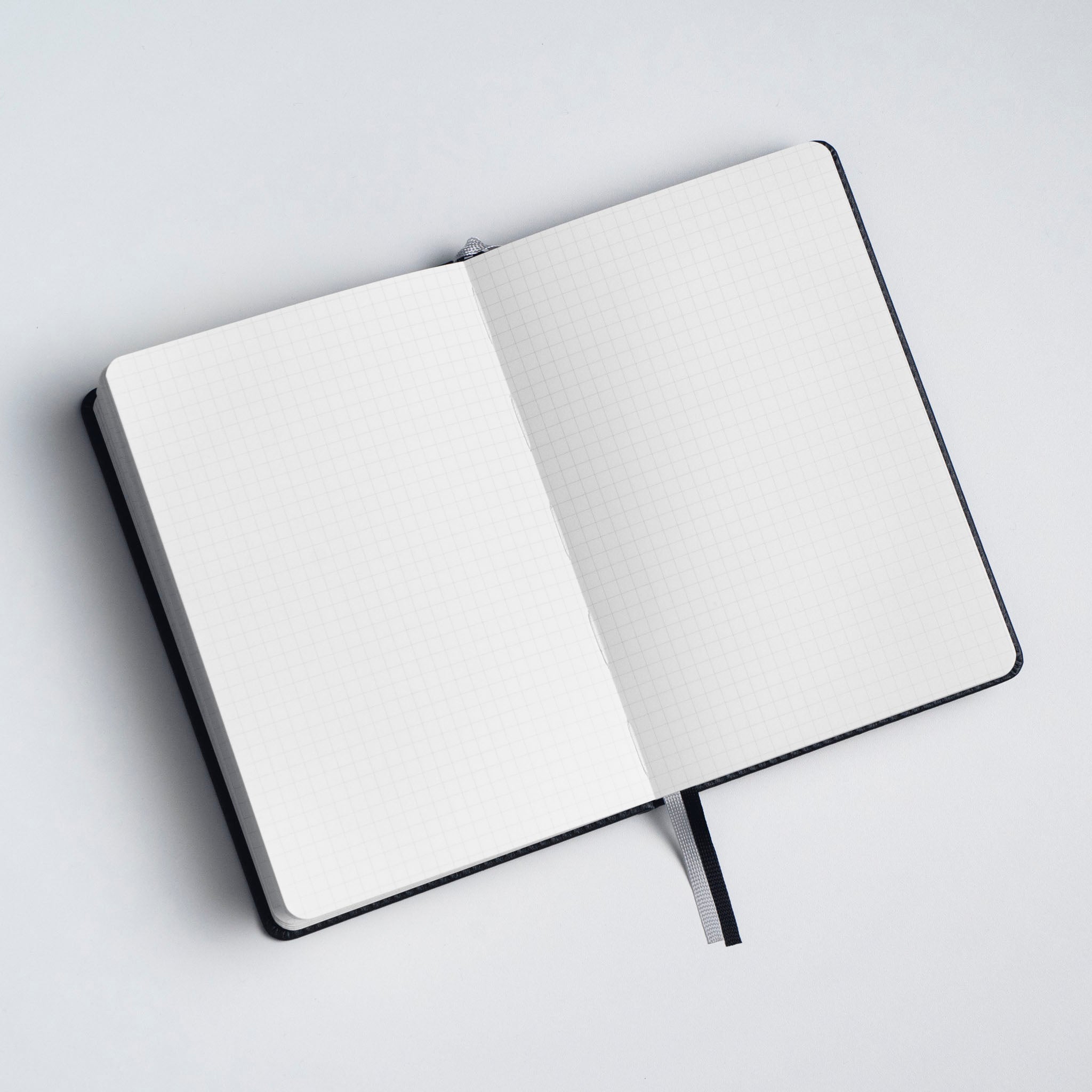 An open notebook with a black cover and gridded pages