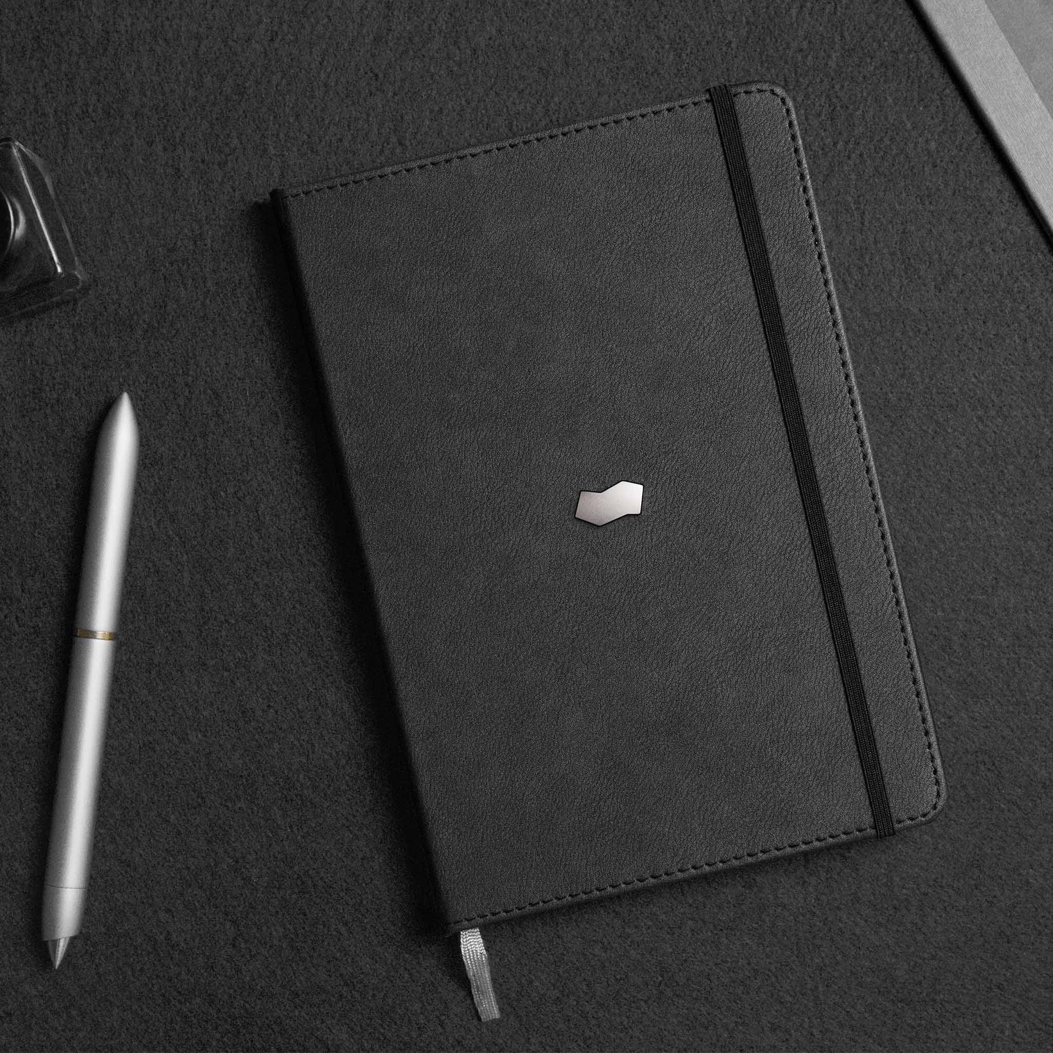 novium leather notebook with a small novium metallic logo embossed on the cover lies on a dark surface