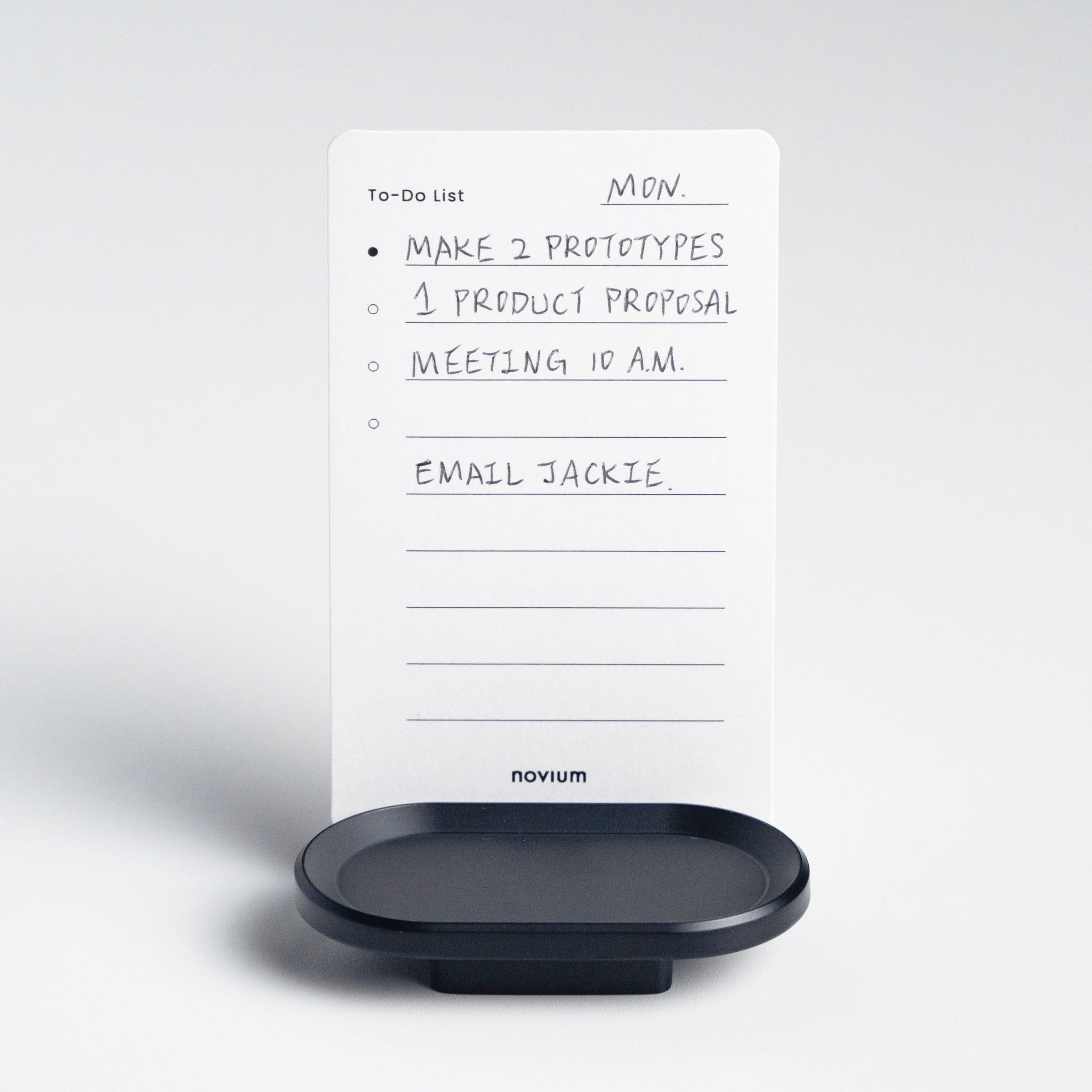 novium black card holder displayed on white desk holding a to-do list card